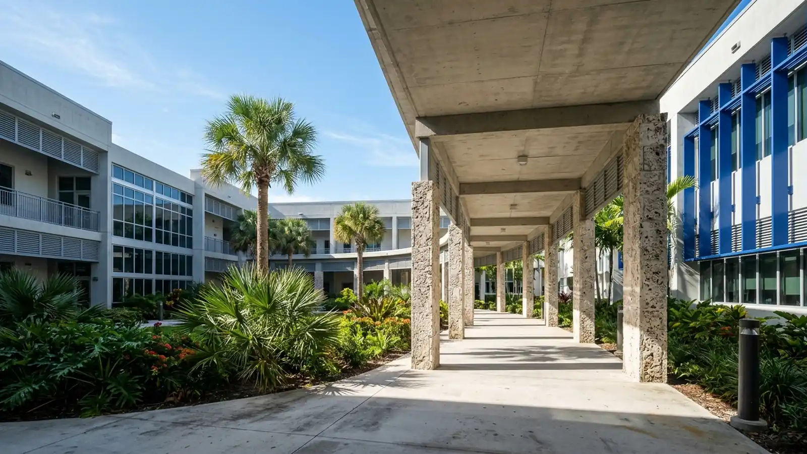 Contemporary Miami-Dade public school courtyard featuring covered concrete breeze-block walkways and subtropical palms